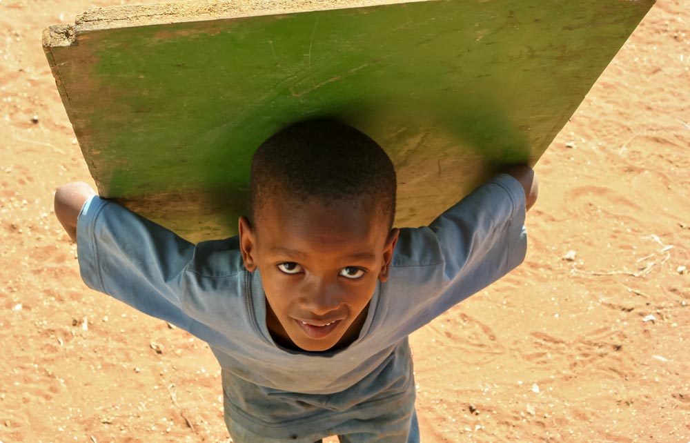 A child carrying a green countertop on their back.